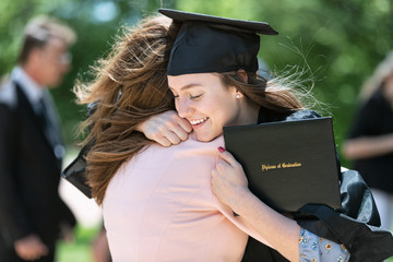 Mother embracing her daughter after graduation ceremony on campus