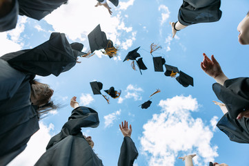 Low angle view of friends tossing their caps in air