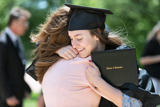 Mother embracing her daughter after graduation ceremony on campus