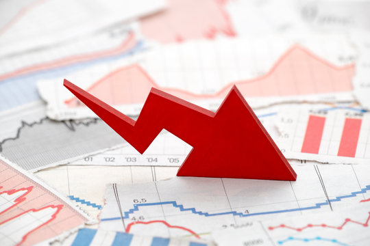 Financial crisis concept with falling red arrow on financial charts from newspapers
