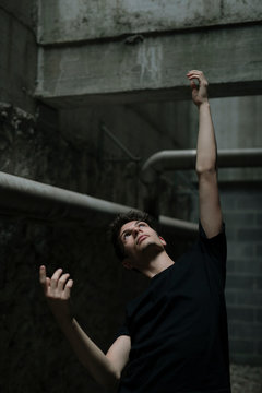 Young man raising hand on dark background