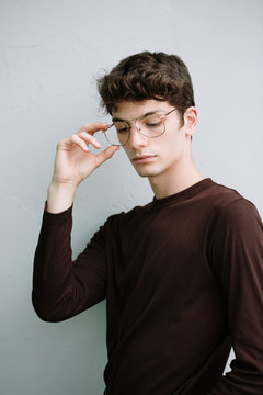 Serious young man with glasses looking down on white background