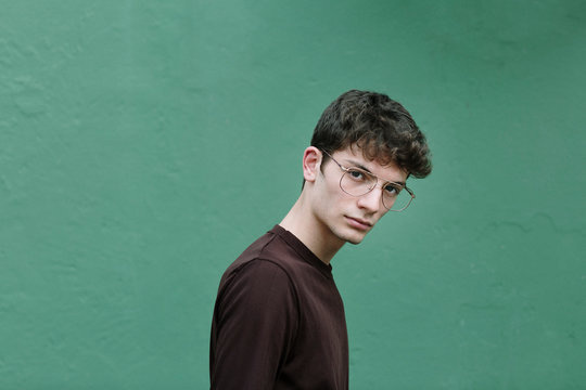 Serious young man looking at camera on green background
