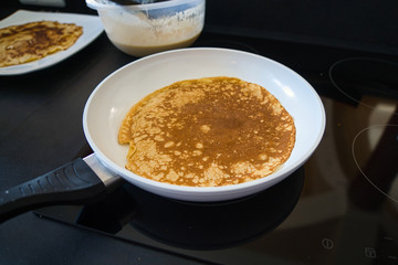 Dessert Nachspeise frischer Vollkorn Crepe Pfannkuchen beim braten in einer weißen Pfanne mit Rührschüssel