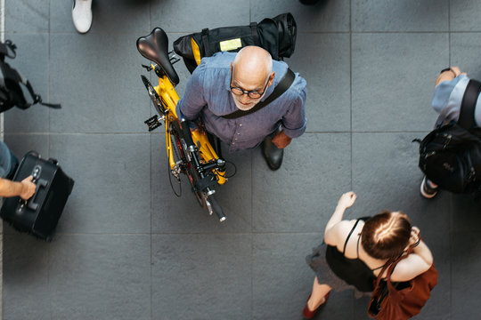Older Man With Folding Bike Waiting in Public