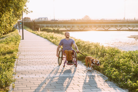 Happy young man in wheelchair enjoying his daily routine with his dog