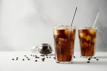 Two glasses of iced coffee and metal straws on a concrete table. Iced coffee on a light background....