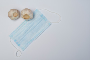 
Medical mask and garlic on a gray background.