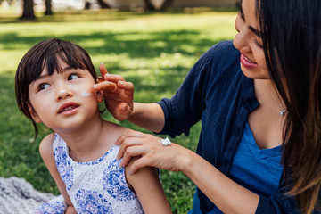 Mother Applies Sunscreen to Daughter
