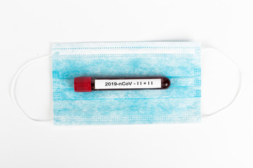 Test tube with Coronavirus blood on medical mask. Coronavirus blood test concept. 2019 nCoV.