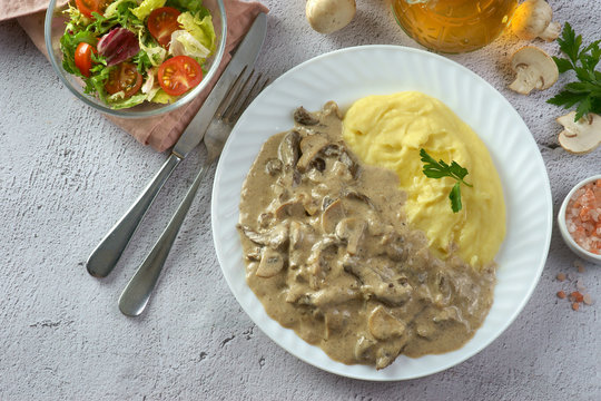 beef Stroganoff with mashed potatoes on a light background with mushrooms and salad
