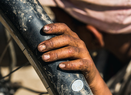 Crop dirty hand of kid on bicycle tire