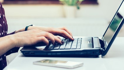 Close up view of female hands typing on laptop computer