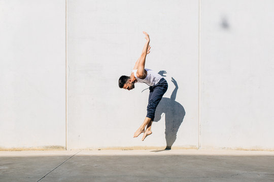 A dancer dancing in front of a concrete wall