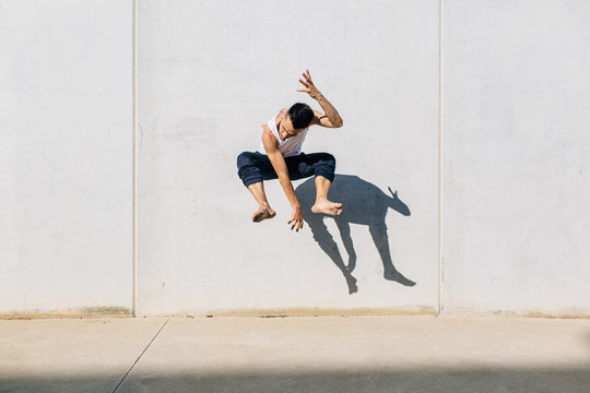 A dancer dancing in front of a concrete wall