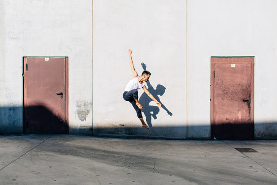 A dancer dancing in front of a concrete wall - Powered by Adobe