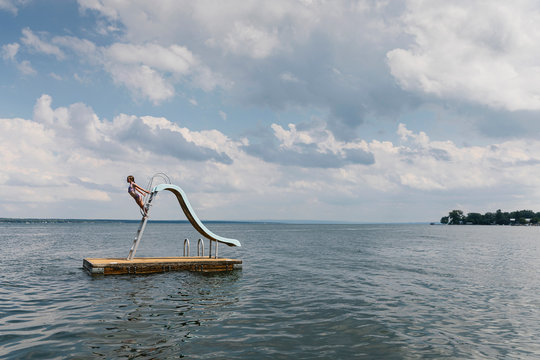 Young Girl Swimming and Playing on Floating Dock Slide At Lake