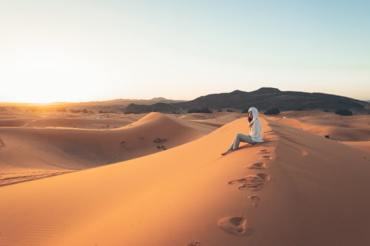 A European woman in a desert wearing white beduin hat