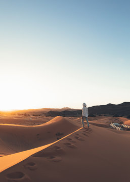 A European woman in a desert wearing a white beduin hat