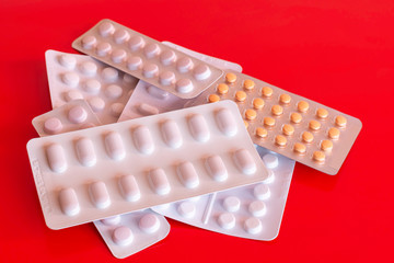 Pile of generic pills blisters on red background.Over Prescribing medication in UK.Packages of...