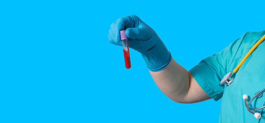 A doctor in a protective suit holds a blood sample with a positive coronavirus in one hand. The concept of the research
