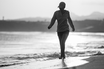 Young woman walking along ocean beach with waves © skumer