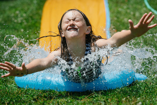 Young Child On Summer Water slide Splashing