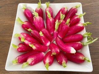 Bunch of radishes in plate on wooden table