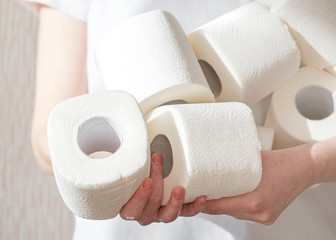 People are stocking up toilet paper for home quarantine from crownavirus. Woman holds many rolls of toilet paper. preparation for quarantine and economic crisis due to coronavirus. Hygiene concept