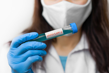 Test tube with vaccine against coronavirus, 2019-nCoV, SARS-nCov, COVID-19 in scientist hand wearing protective mask and blue gloves.