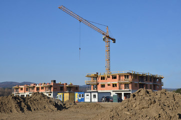 Two buildings in process of construction with tower crane behind them