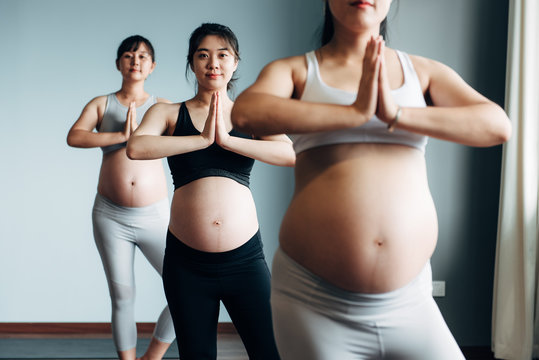 Pregnant young women practicing yoga in gym class