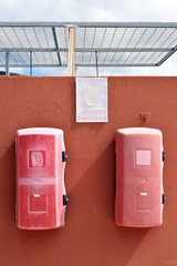 Painted Wall with Two Weathered Red Fire Extinguishers attached next to Faded Sign 