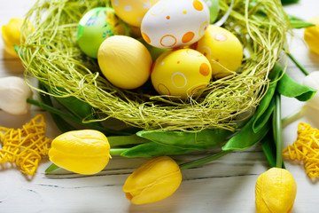 Happy Easter. Congratulatory easter background. Easter eggs and flowers. Background with copy space. Selective focus. Top view.