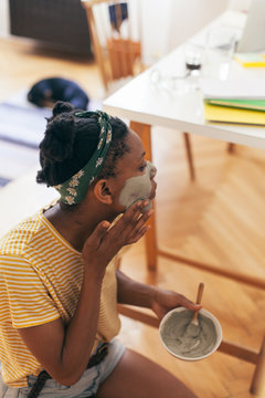 African American woman applying facial mask