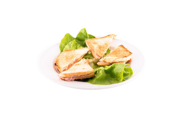Ham and cheese sandwich decorated with green salad. Served on a white plate, melted on a white background. The photo is suitable for feeding mei restaurant. Dish of Montenegrin cuisine.
