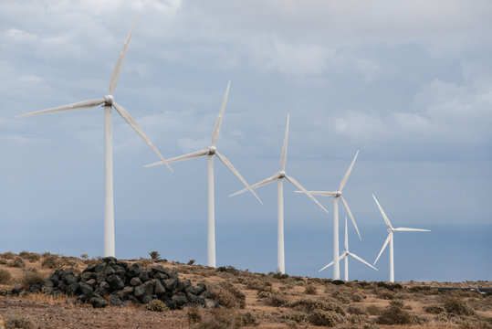Many wind turbines on high hill among stones.