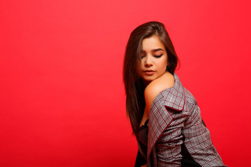 Fashion woman  in suit on red background. Stylish model in studio. Sexy woman in blazer.  Portrait of an attractive female model posing on red background isolated.