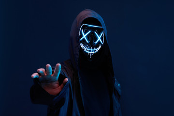 Dangerous hooded hacker. Internet, cyber crime, cyber attack, system breaking and malware concept. Anonymous. Dark background.
