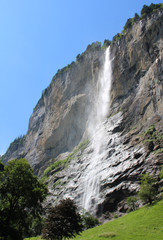 View of the spectacular 300m Staubbach Waterfall in Lauterbrunnen, in the Bernese Oberland in Switzerland, in summer with blue sky.