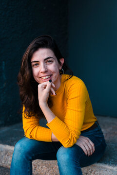 Young shy woman with skin acne seated in street smiling