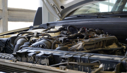 The hood is open on the car and the top of the engine is visible. Service and car repair concept.