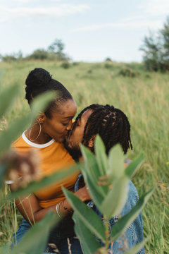 A young engaged african american couple posing for pictures in a meadow
