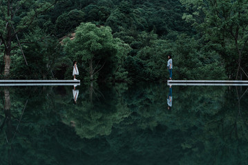 Mother and daughter standing on piers in lake