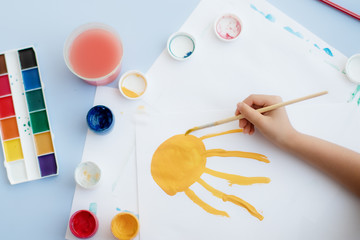 a child's hand with a paint brush draws at a table in a kindergarten or in a development center