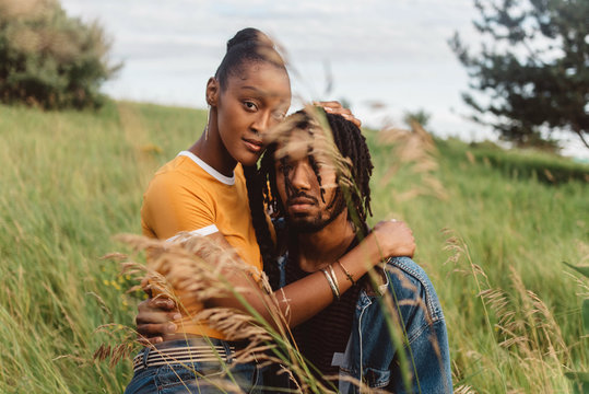 A young engaged african american couple posing for pictures in a meadow
