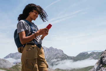 Happy brown skinned woman smiling on the phone the Europe Peaks in Asturias