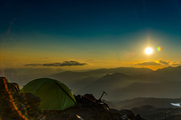 Fototapeta na wymiar Mountain camp, tent on the background of the sun and mountains
