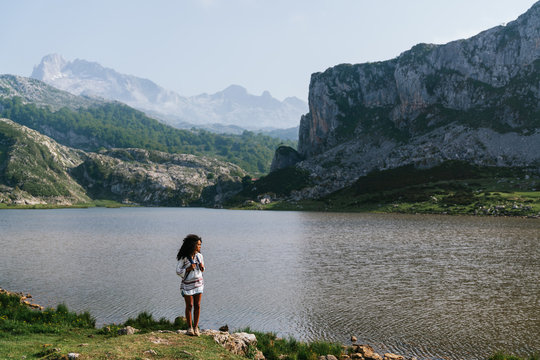 Happy brown skinned woman standing on a lake at Covadongas, in Europe Peaks in Asturias