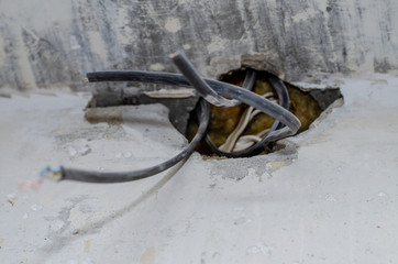 repair in the apartment. wires stick out of a hole in a concrete wall. The owner of the house is waiting for an electrician.